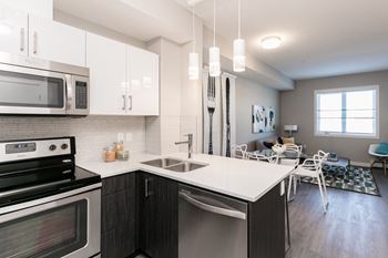 A modern kitchen with a stove, microwave, and sink.